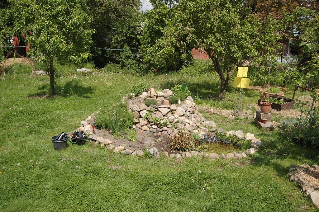 Fertig gebaute Kräuterspirale aus Stein mit Teich
